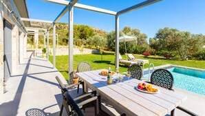 A covered outdoor area with a pool, dining table, chairs, and a view of the surrounding landscape. - Villa Angelos - Three Bedroom Villa, Sleeps 6 (Ionian Islands)