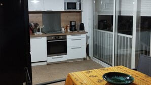 A compact kitchen with white cabinets, a microwave, a coffee maker, and a dining table with a bowl. - House 6 pers. direct beach access(100 meters walk) (Borgo)