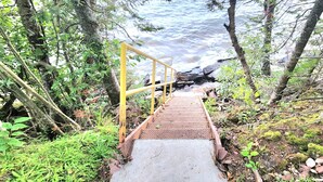 A concrete staircase with metal railings leading down to a rocky shoreline.