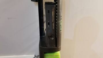 A black and green electric toothbrush with a charging base and a control panel.