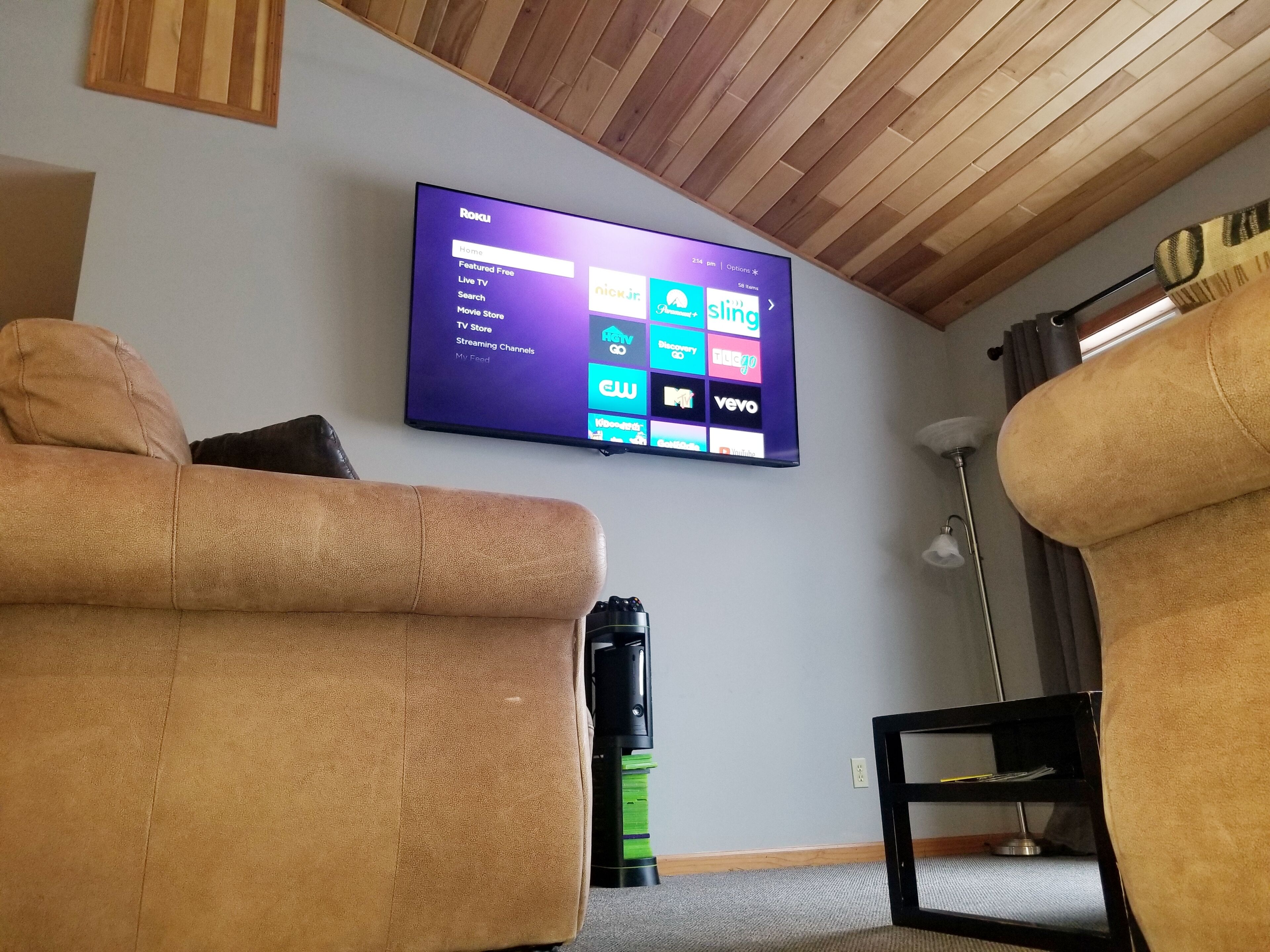 Un salon avec un téléviseur à écran plat fixé au mur, qui affiche l’interface d’un service de diffusion en continu.