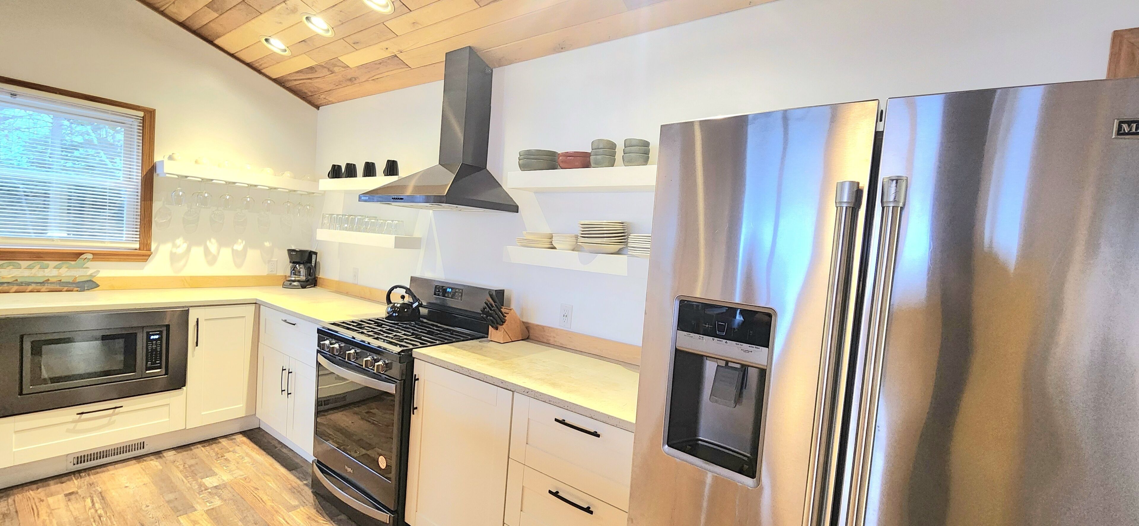 Une cuisine moderne équipée d’appareils électroménagers en acier inoxydable, d’un four encastré, d’une cuisinière à gaz et d’un réfrigérateur.