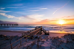 A beach with a wooden staircase leading to a pier.