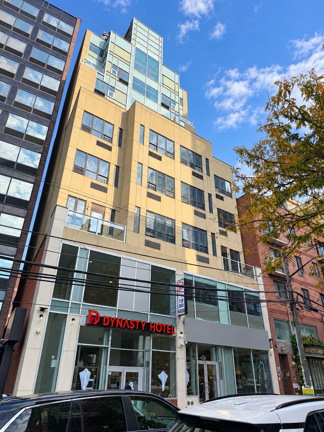 A multi-story hotel with a prominent 'Dynasty Hotel' sign, large windows, and a modern architectural design.