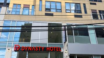 A modern hotel building with a prominent 'Dynasty Hotel' sign.