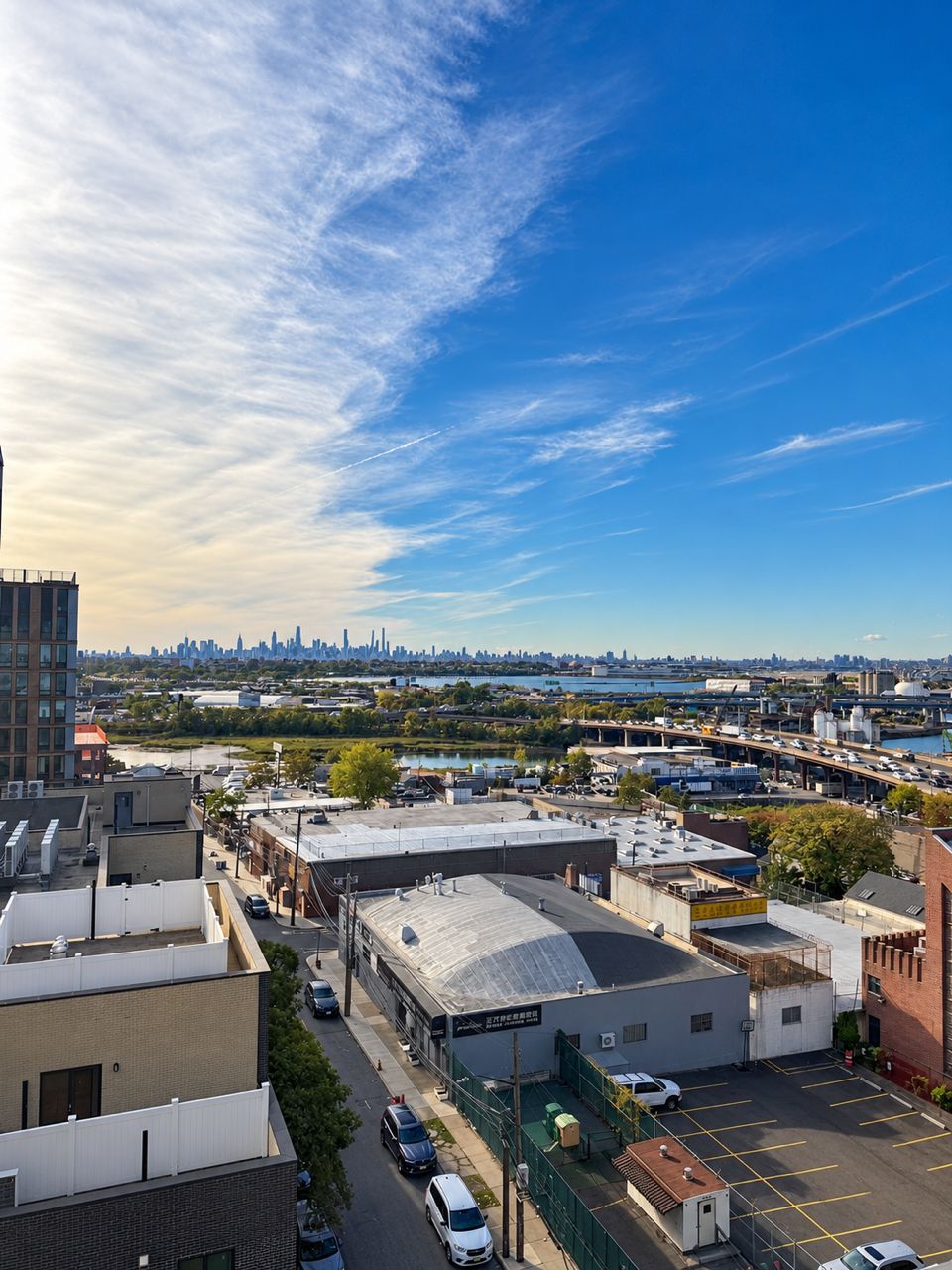 A cityscape with a clear sky, buildings, and a parking lot.