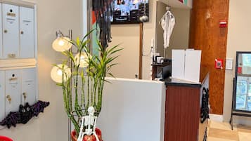 Un mostrador de recepción con una planta, una figura esquelética y una pantalla en la pared.