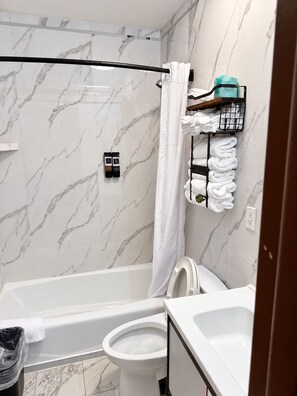 Ein Badezimmer mit Badewanne, Toilette und Duschbereich.