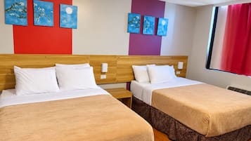 A hotel room with two beds, a red and purple wall, and artwork.