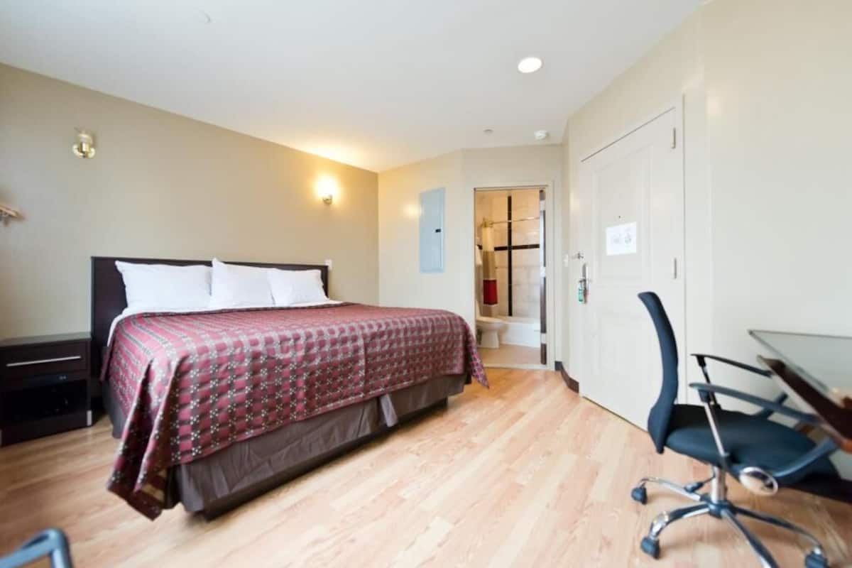 A bedroom with a bed, a desk, and a chair.
