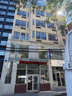 A building with a glass facade and a sign for the Dynasty Hotel. - Dynasty Hotel and Suites New York LaGuardia Hotel (Flushing)