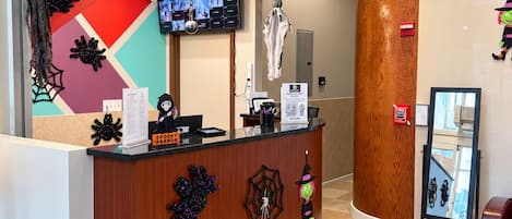 Una recepción con diseño moderno, un televisor de pantalla plana y decoraciones de Halloween.
