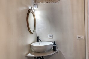 Ein Badezimmer mit einem weißen Waschbecken, einem Spiegel und einer Leuchte.