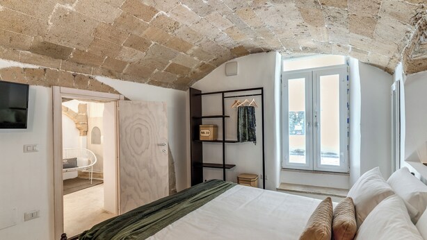 A bedroom with a brick ceiling, a bed with pillows, a wardrobe, and a window with a view. - La Cummare - Le Case di Valentina (Gallipoli)
