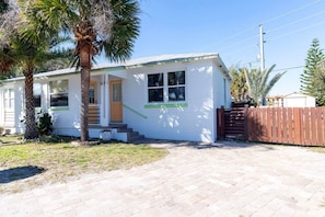 A single-story house with a front porch, a wooden fence, and a palm tree. - Anastasia Lodge (St Augustine Beach)