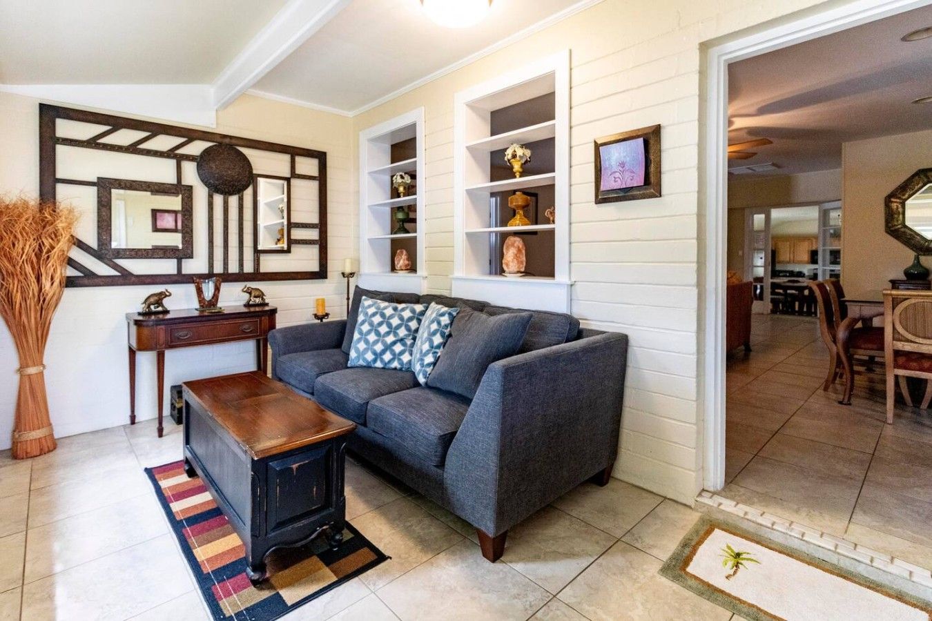 A living room with a sofa, a coffee table, a fireplace, and a dining area visible in the background.