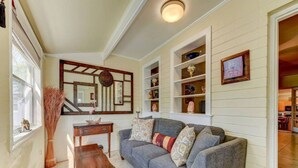 A living room with a grey sofa, a wooden side table, and a mirror above a fireplace. - Anastasia Lodge (St Augustine Beach)