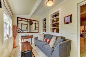 A living room with a grey sofa, a wooden side table, and a mirror above a fireplace. - Anastasia Lodge (St Augustine Beach)