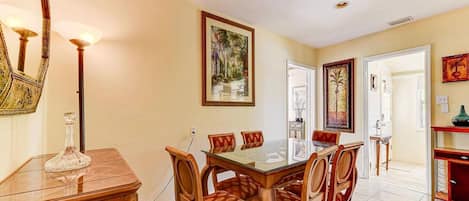 A dining area with a glass-top table, wooden chairs, and a chandelier.