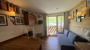Une pièce chaleureuse avec une table à manger en bois, un canapé et un balcon doté d’une balustrade en bois.