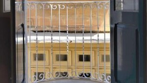 A view through a glass door to a balcony with a metal railing, a tiled floor, and a building facade with windows and decorative moldings. - Citta Cospicua Suites - Polverista Suite (Bormla)