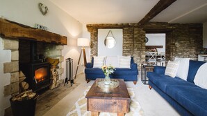 A cozy living room with a stone fireplace, a blue sofa set, and a coffee table with a vase. - Field View - sleeps 5 guests  in 3 bedrooms (Tarlton)