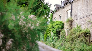 A narrow, unpaved path leading to a stone building with arched windows and ivy-covered walls. - Field View - sleeps 5 guests  in 3 bedrooms (Tarlton)