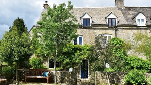 A stone house with multiple windows, a wooden bench, and lush greenery. - Field View - sleeps 5 guests  in 3 bedrooms (Tarlton)