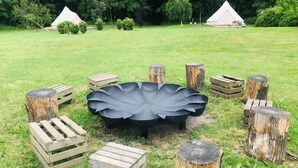 A rustic outdoor seating area with a central black metal table surrounded by wooden crates and tree stumps.
