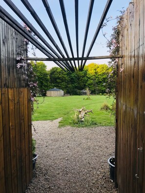 A wooden pergola structure with a gravel pathway leading to a grassy area. - Luna Lodge, nestled in field and woodland surroundings (Dunsdale)