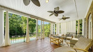A covered porch with wooden flooring, white columns, and ceiling fans. - Norris Lake Manor-Exquisite Waterfront with *Private Dock *Pool *Hot tub *Game room  (Caryville)