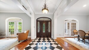 A spacious foyer with a checkered floor, a chandelier, and a dining area with chairs and a table. - Norris Lake Manor-Exquisite Waterfront with *Private Dock *Pool *Hot tub *Game room  (Caryville)