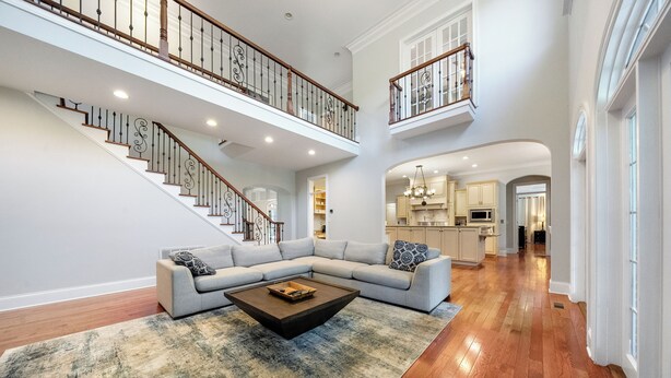 A spacious living area with a large sectional sofa, a coffee table, and a staircase leading to an upper level. - Norris Lake Manor-Exquisite Waterfront with *Private Dock *Pool *Hot tub *Game room  (Caryville)