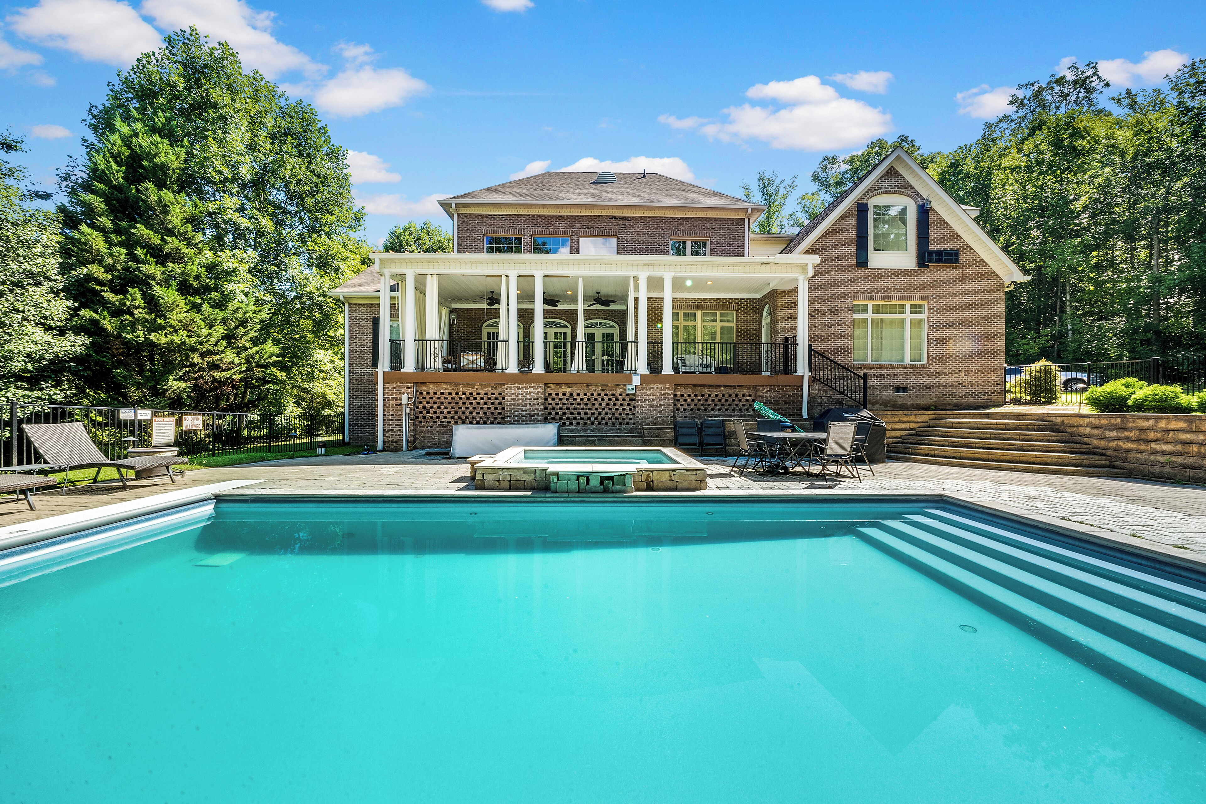 A two-story house with a swimming pool, a covered patio, and a brick exterior.