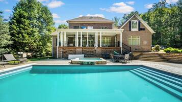 A two-story house with a swimming pool, a covered patio, and a brick exterior.