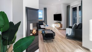 A modern living room with a fireplace, a flat-screen TV, a sofa, and a dining area. - Admiralsdeck Panoramablick, Finnische Sauna, 3 Baeder, Fahrstuhl, 2 Terrassen (Olpenitz)