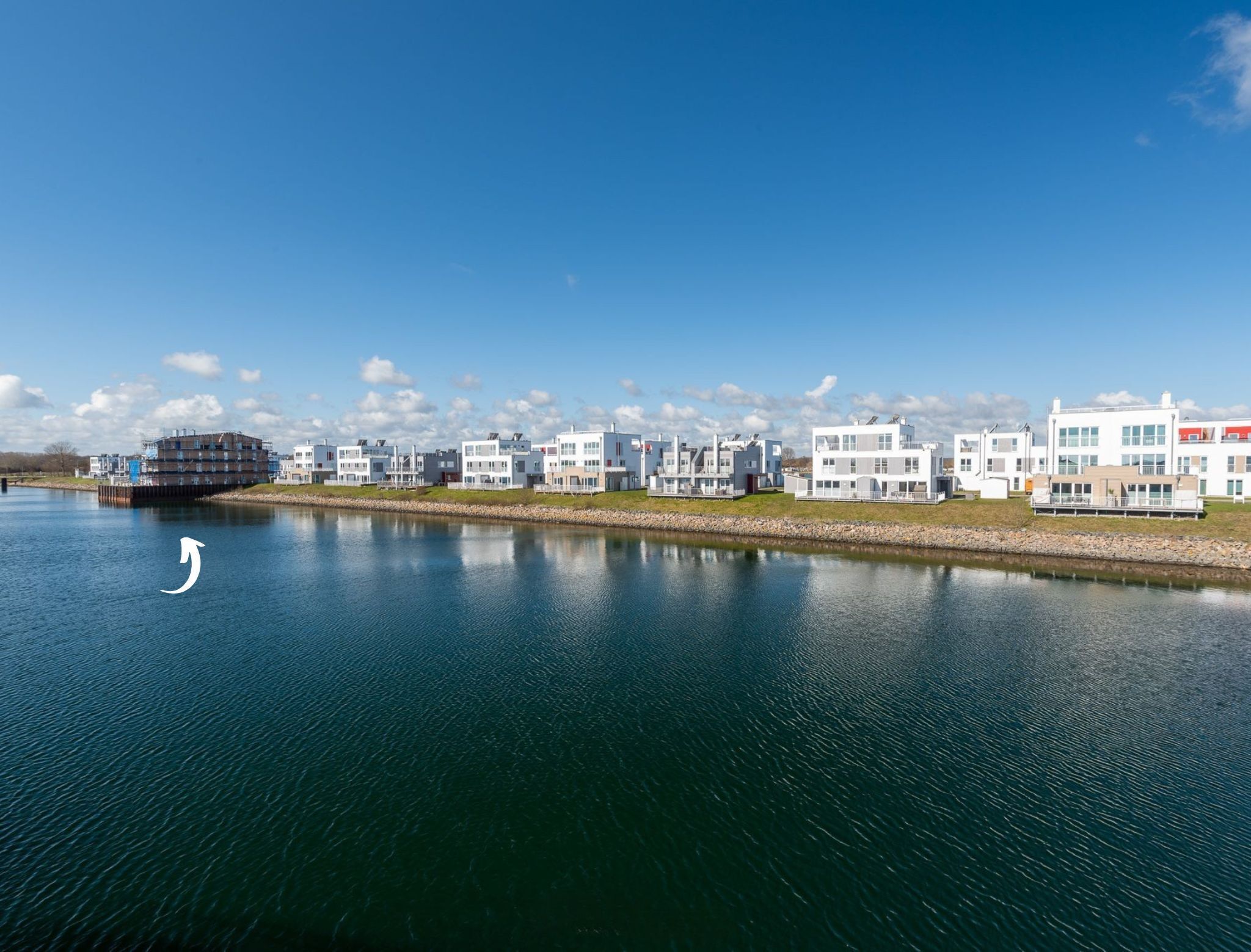 A waterfront property with modern buildings, a dock, and a calm river.