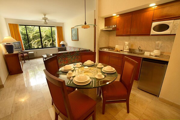 A modern kitchen with a dining area, equipped with a refrigerator, microwave, and a dining table set for four.