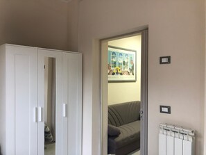 Una stanza con un armadio bianco, un divano grigio e un quadro appeso al muro.