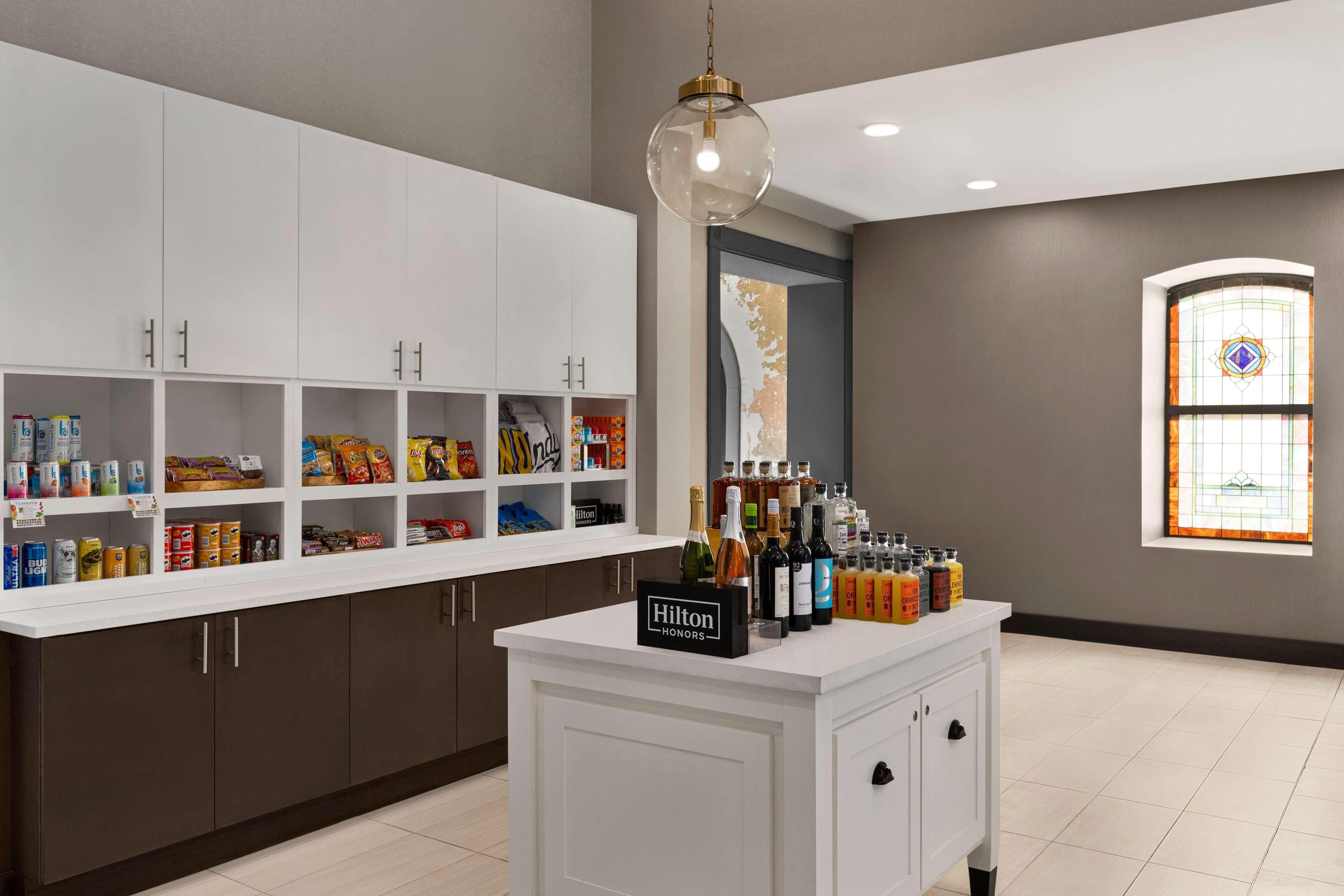 Una cocina con armarios blancos, un minibar y un letrero de minibar que dice "Hilton Honors".