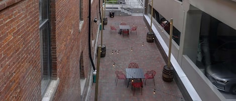 A courtyard with brick walls, a table with chairs, and string lights.