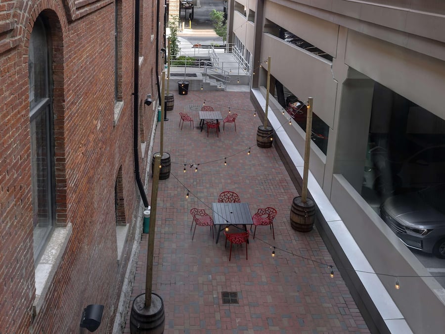 A courtyard with brick walls, a table with chairs, and string lights.