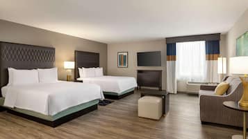 Ein Hotelzimmer mit zwei Betten, einem Fernseher, einer Couch und einem kleinen Tisch.