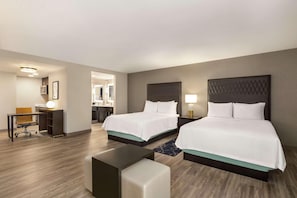 Une chambre d’hôtel avec deux lits, un bureau et une chaise.