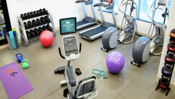 Ginásio com esteiras, elípticos e diversos bolas de exercício.