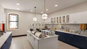A modern kitchen with a central island, white cabinets, and a large window with stained glass.