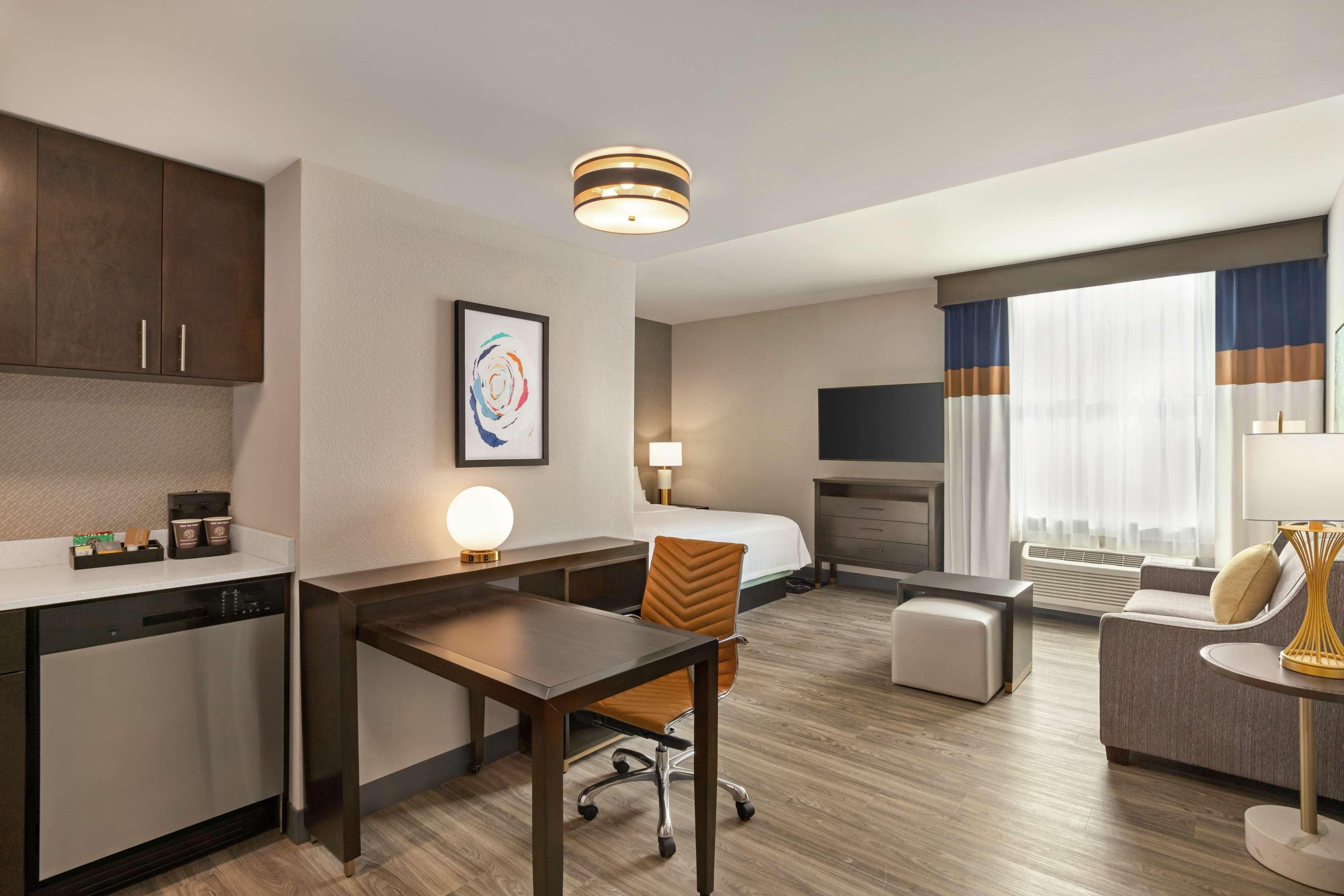 Ein Hotelzimmer mit Küchenzeile, Essbereich, einer Couch, einem Fernseher und einem Kamin.