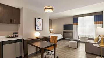 Ein Hotelzimmer mit Küchenzeile, Essbereich, einer Couch, einem Fernseher und einem Kamin.