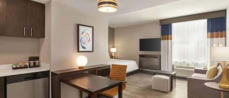 Une chambre d’hôtel équipée d’une kitchenette, d’un coin repas, d’un canapé, d’une télévision et d’une cheminée.