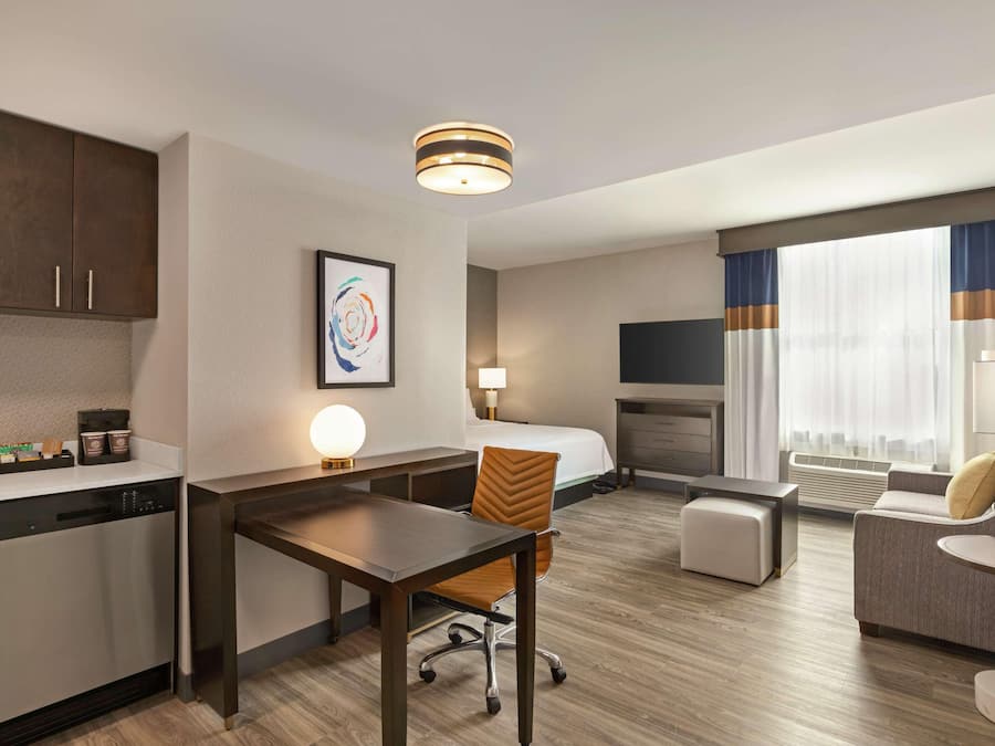 Ein Hotelzimmer mit Küchenzeile, Essbereich, einer Couch, einem Fernseher und einem Kamin.